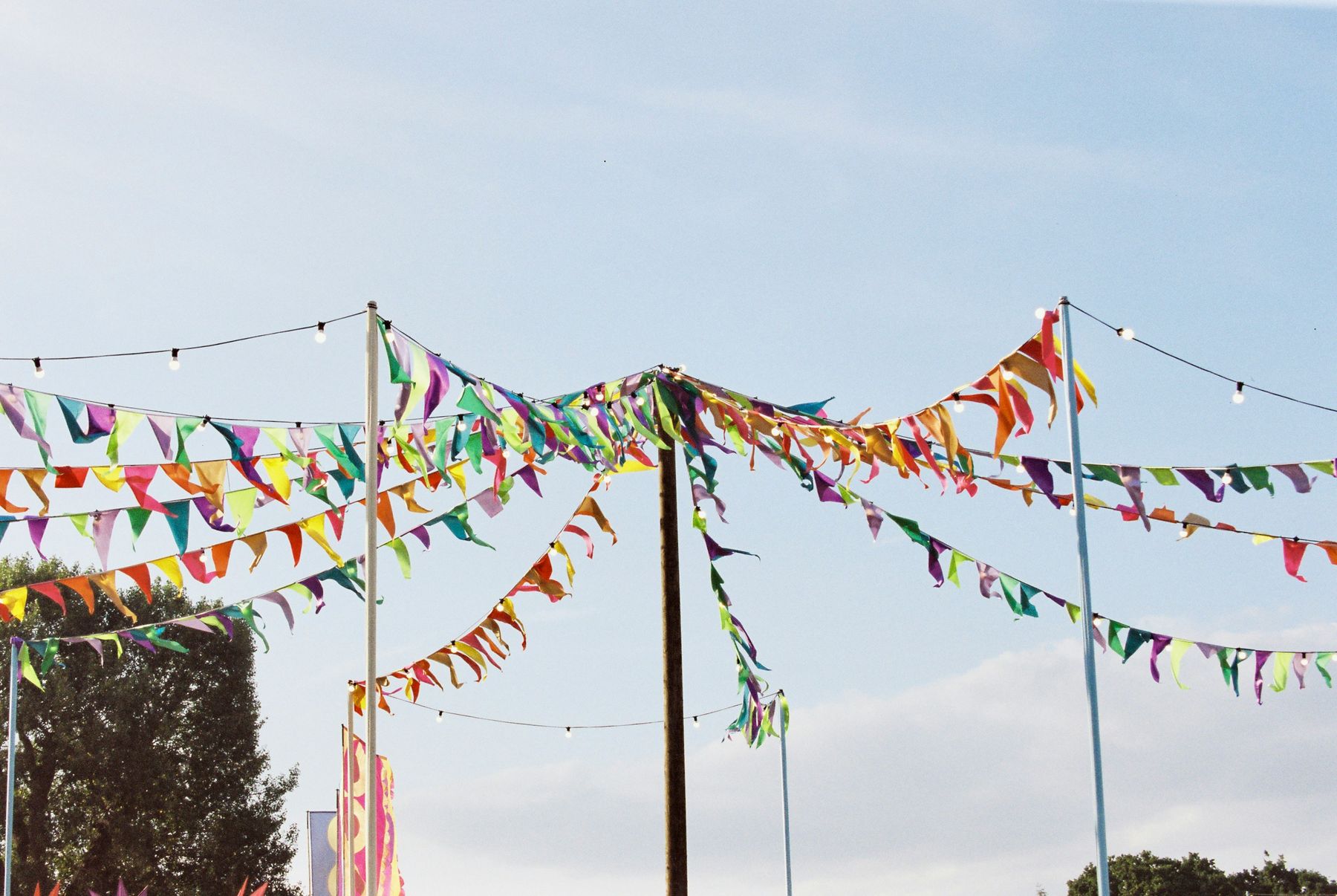 Strings of colorful bunting flags and festoon lights against a big open sky