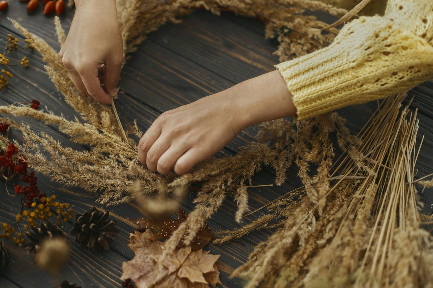Hands weaving an autumn wreath